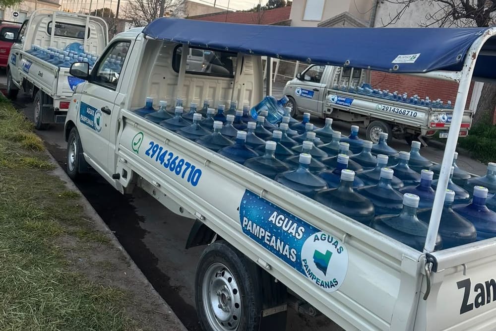 Camioneta de Aguas Pampeanas con el teléfono de WhatsApp pintado en la puerta, cargada de bidones