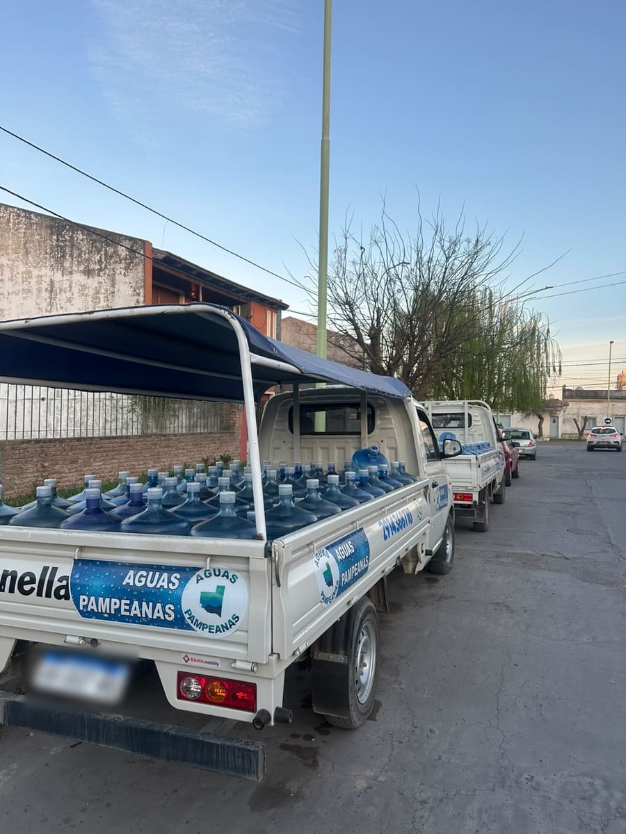 Las camionetas de Aguas Pampeanas en fila frente a la oficina, cargadas de bidones